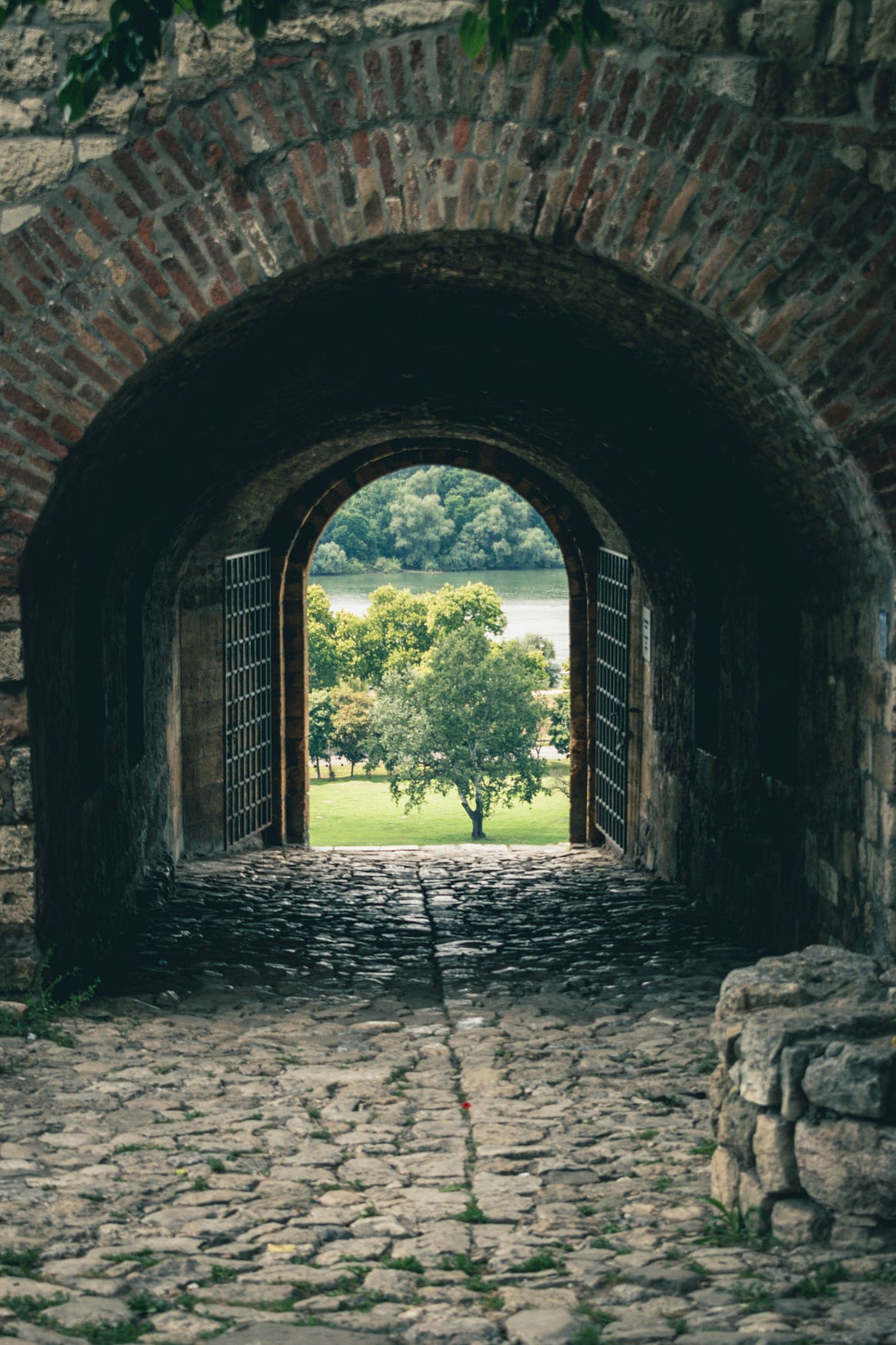 Picture of a stone path leading to an open gate with a meadow in the background