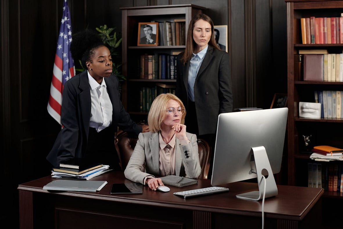 Older woman at desk with US flag and staff