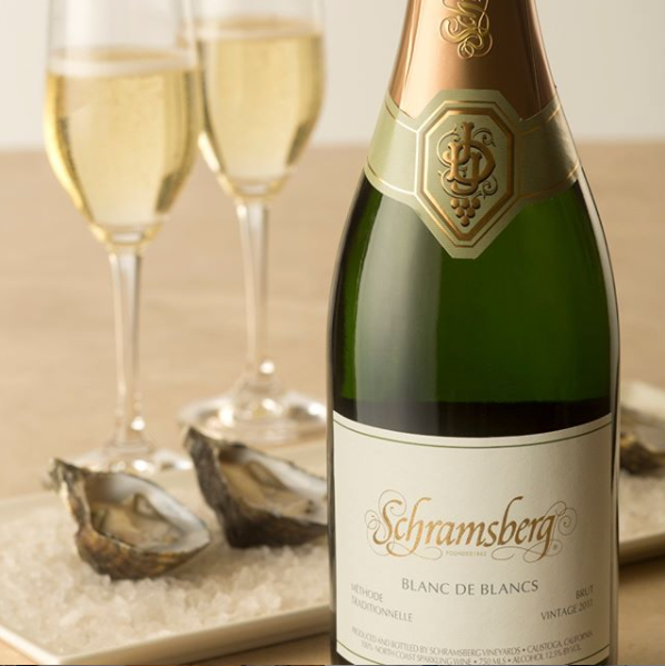 Closeup of a bottle of Schramsberg Blanc de Blanc in front of two full wine glasses.