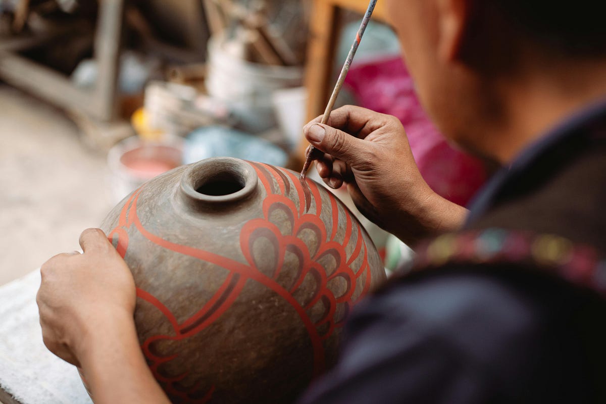 'a person painting a vase'