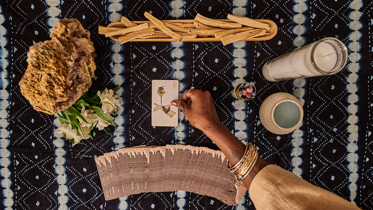 A tarot spread laid out on a table with cards like The Tower, The Star, and The Hermit, surrounded by crystals and candles.