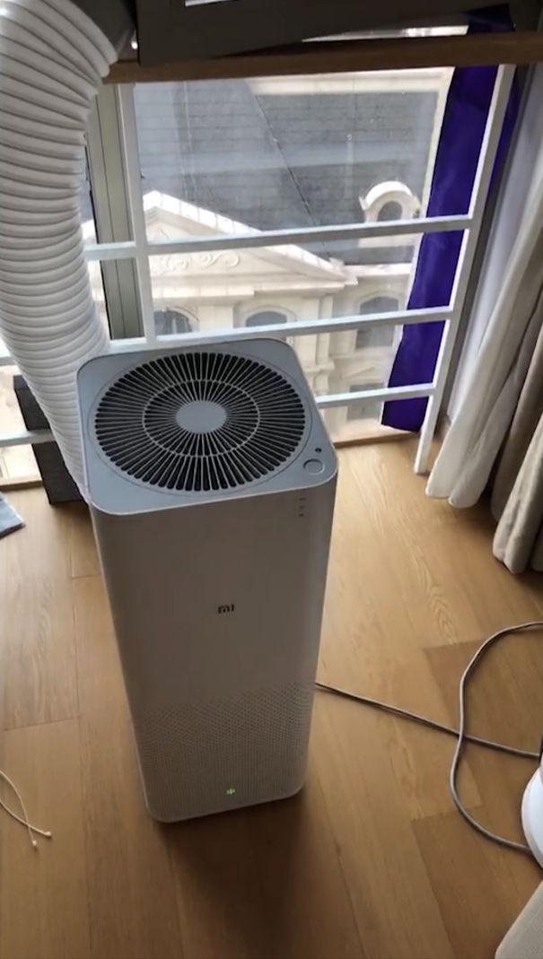 An air purifier with a duct leading to a window.