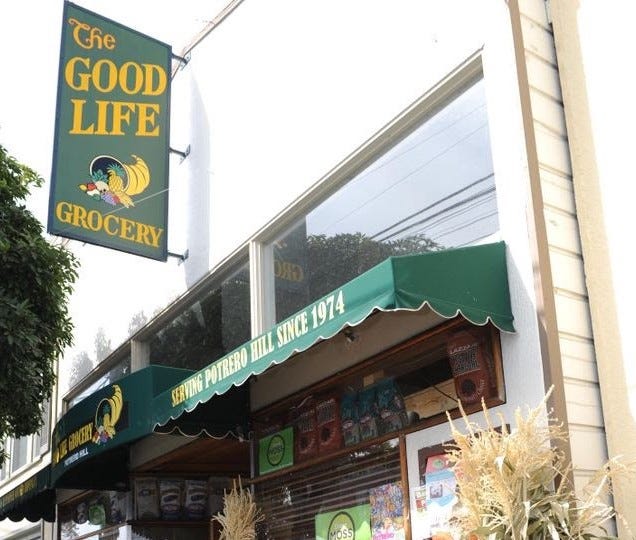 The Good Life Grocery’s storefront with its green awning and painted sign with a cornucopia.