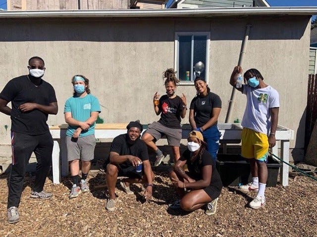 A group of volunteers posing outside a stucco house, wearing masks.