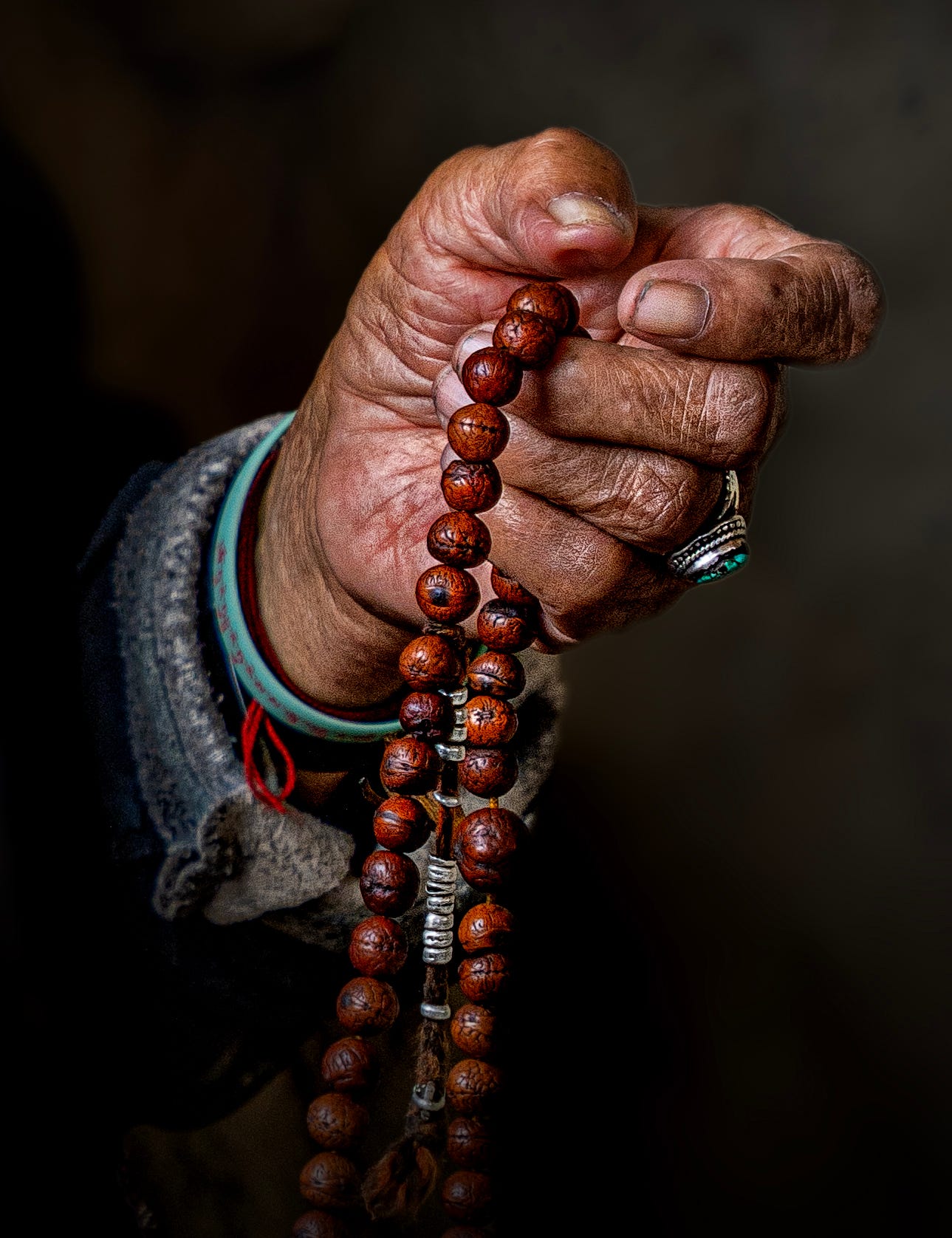 Weathered hands holding prayer beads — a reflection of faith in the Himalayas.