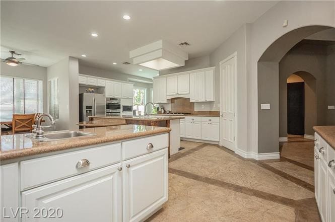 A white kitchen with tan tile floors.