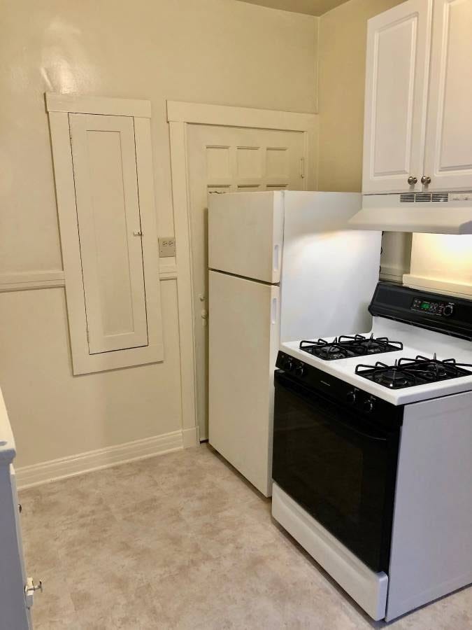 A stove with a fridge next to it that’s completely blocking a door.