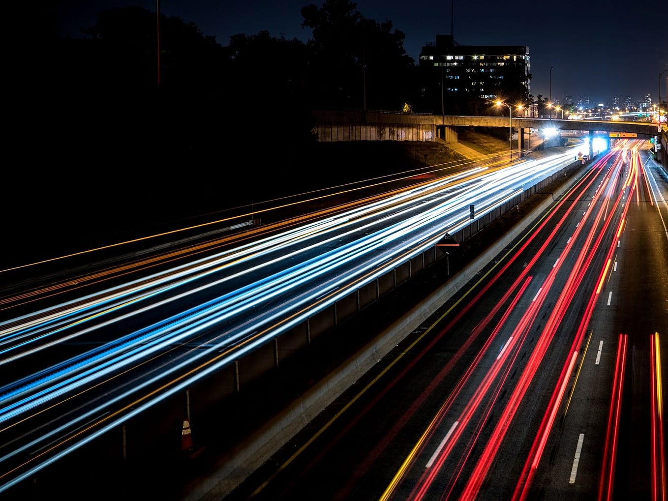 Long exposure picture of a highway, where the lights from the vehicles are really long continuous lines covering the road (and vehicles are actually not visible), giving a sense of really high speeds.