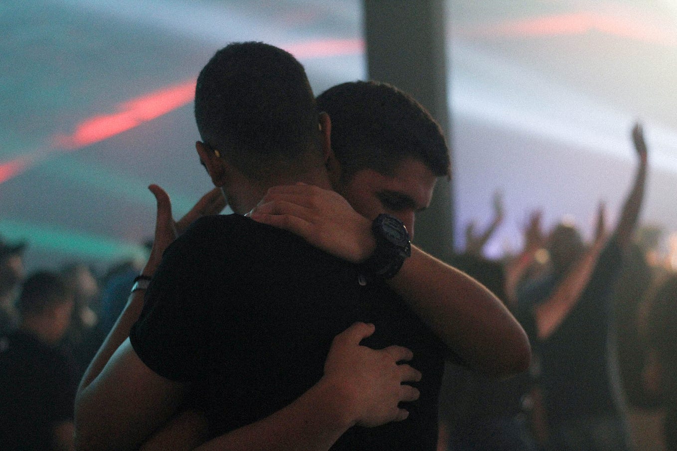 Two men with short dark hair hugging. They appear to be White.