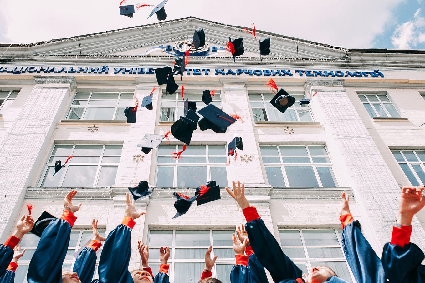 A group of graduating students throw their grad caps in the air in a show of celebration.