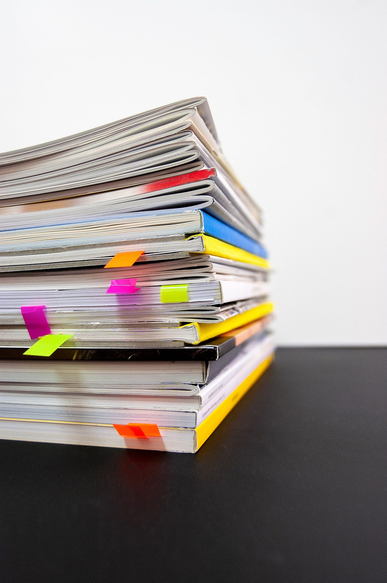 A stack of printed magazines, with small post-it notes poking out from inside