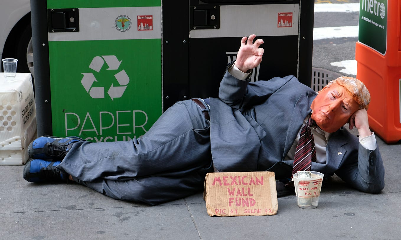 Image of a Donald Trump imposter laying on the ground and begging for money.