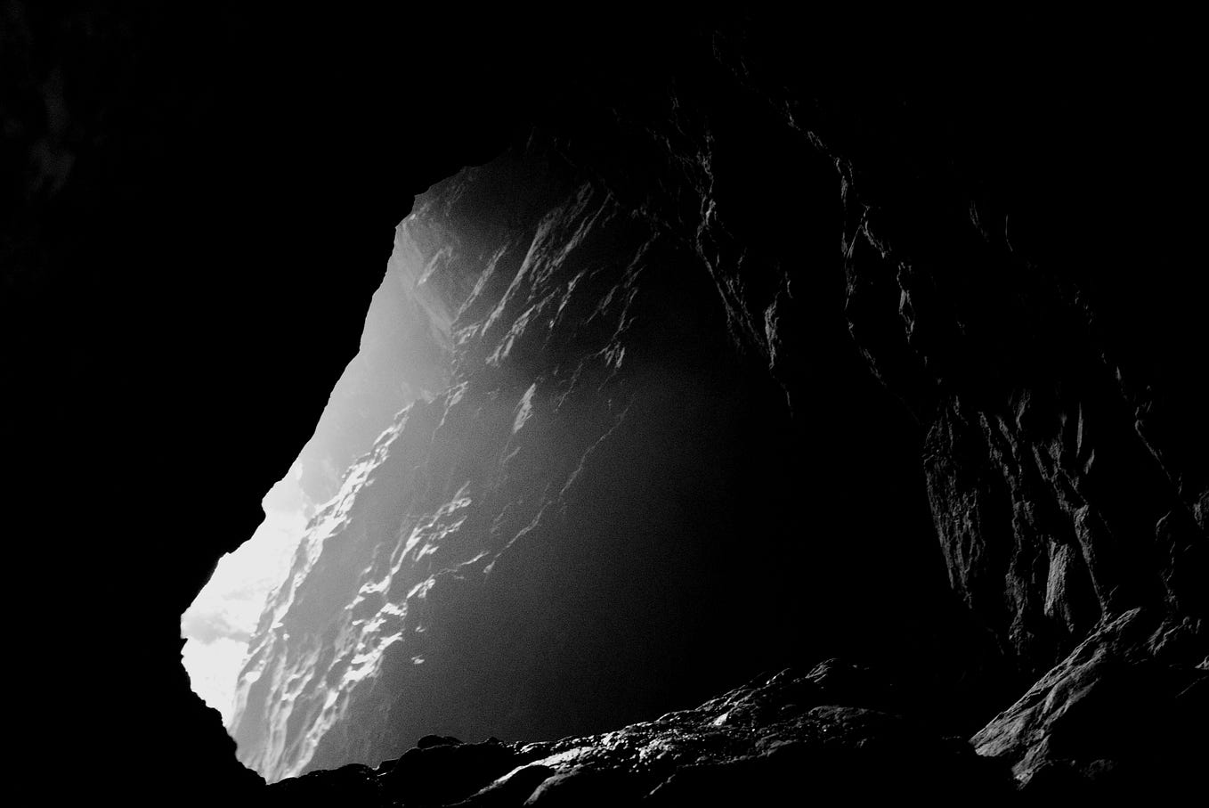 a cave entrance from the inside. bright light illuminates craggly rocks.