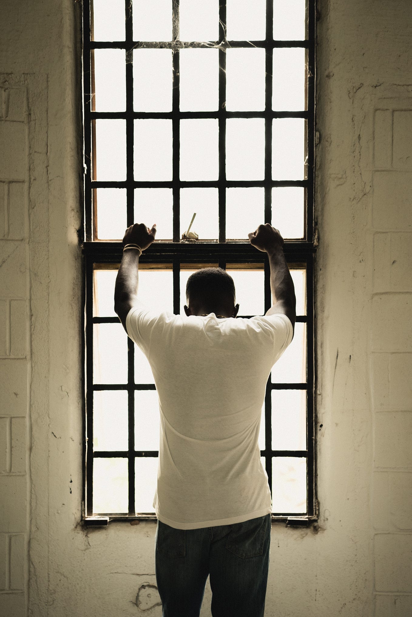 A Black man looking down through a prison window.