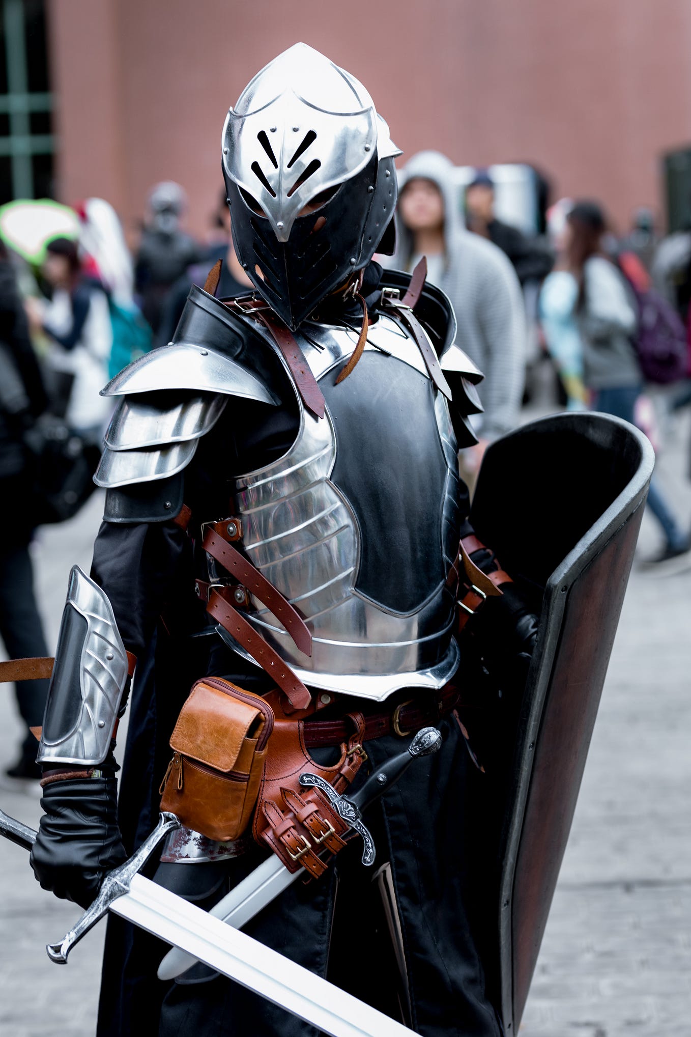 A man standing with armor on and many people behind and beside him.