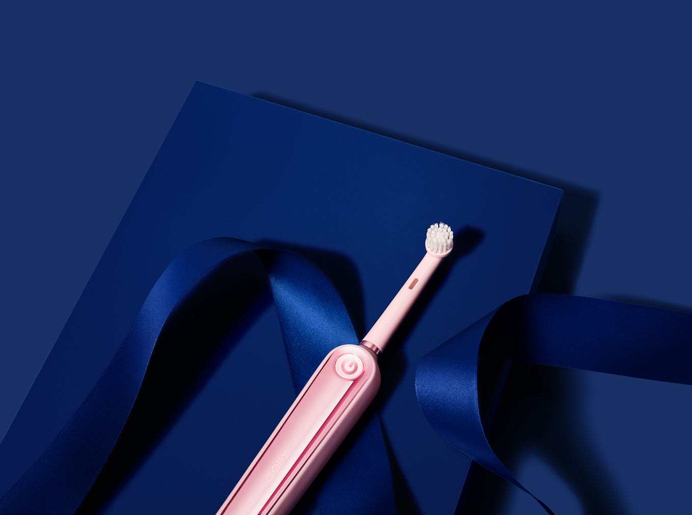 Pink electric toothbrush on a deep blue background