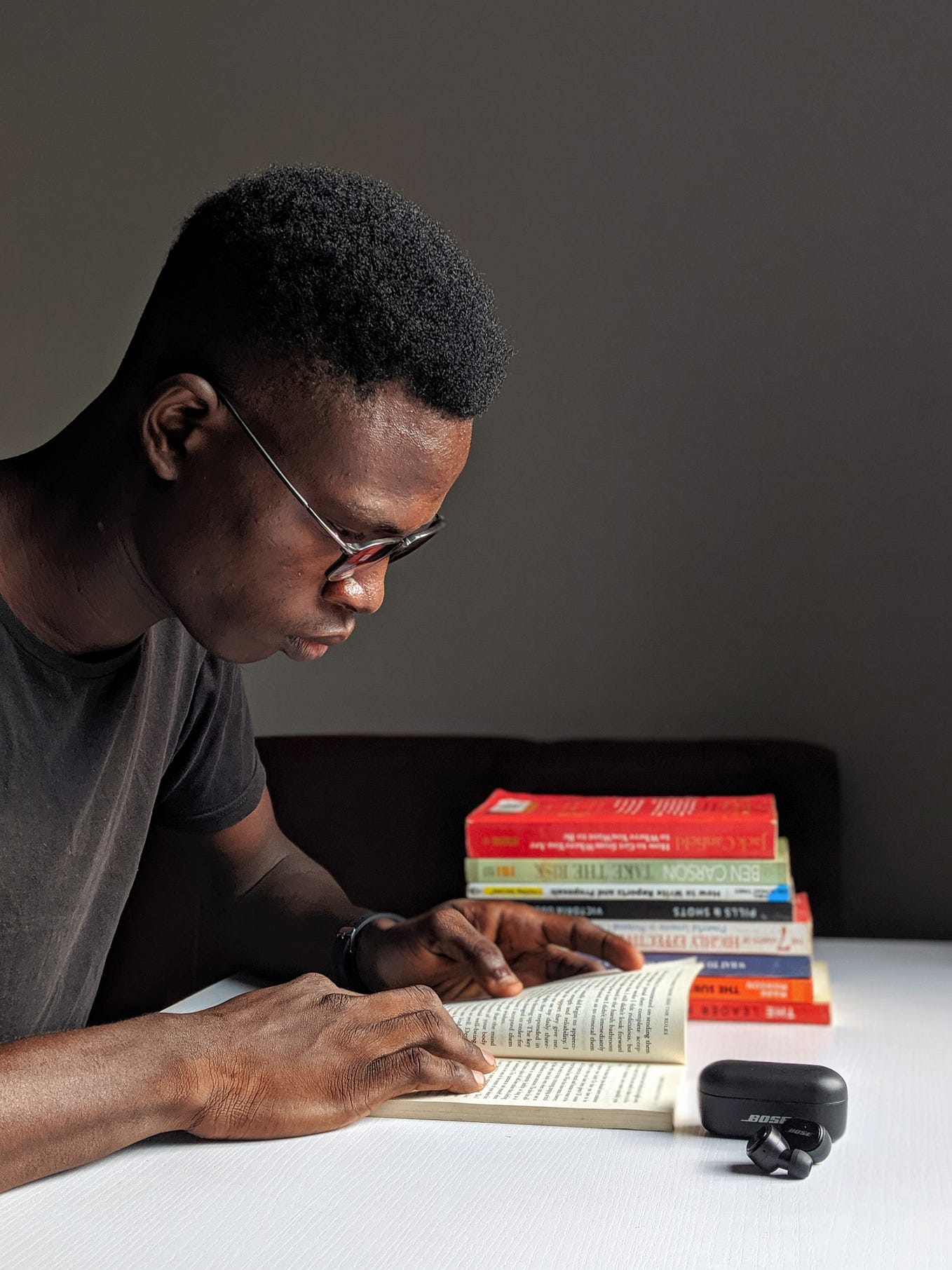 Black man reading at a desk with other books stacked next to him.