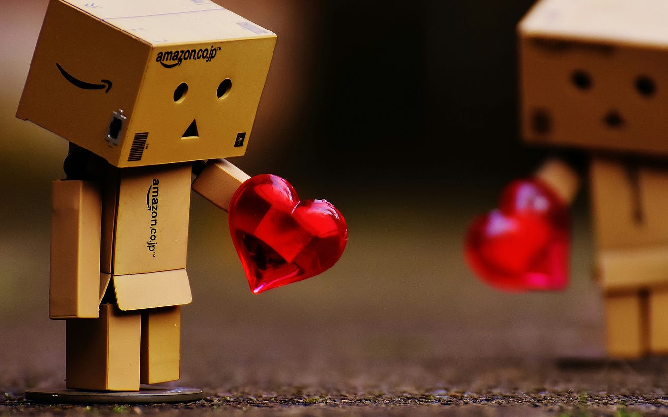 Little box person holding a red plastic toy gem heart