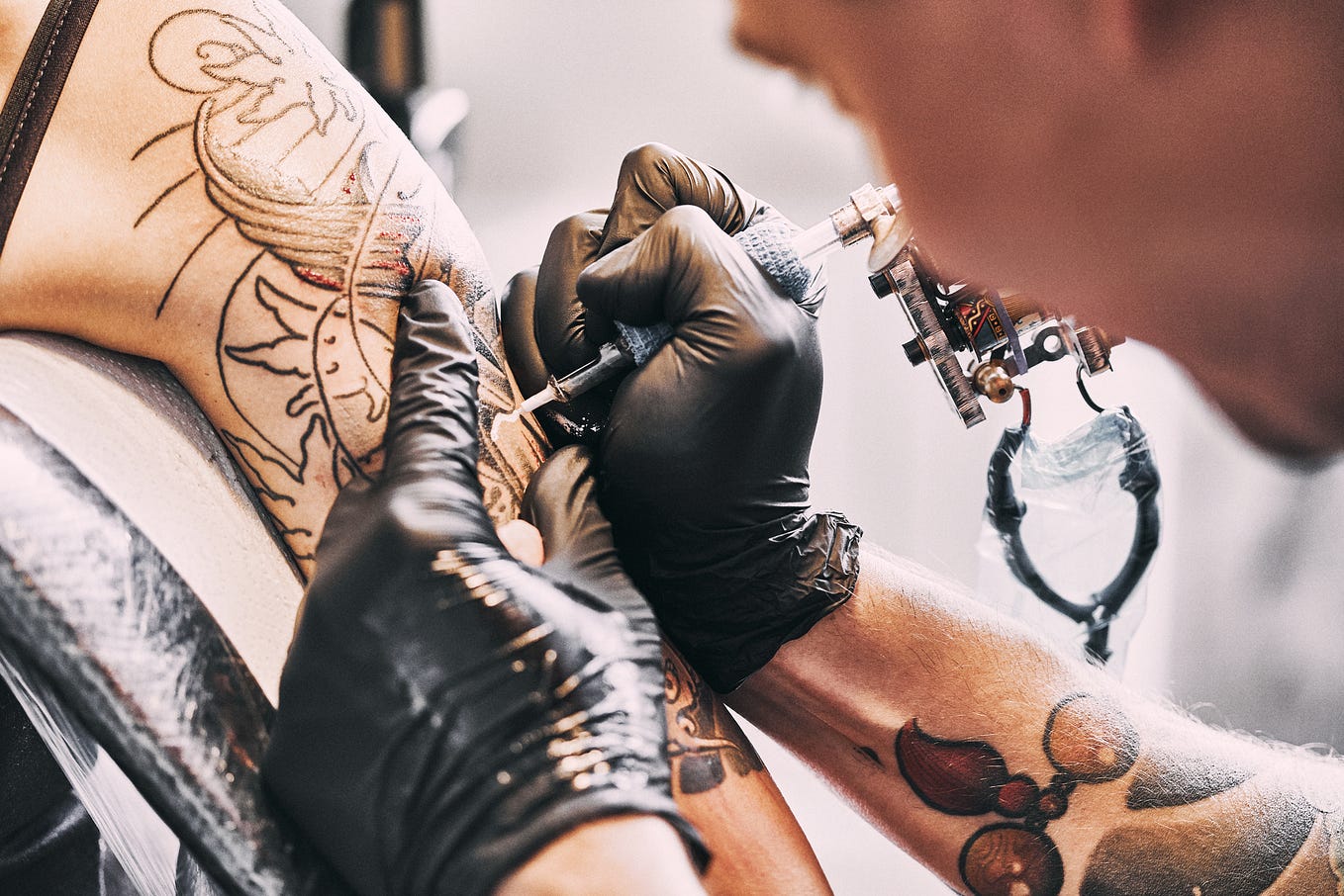 Tattoo Artist making a tattoo on a shoulder.