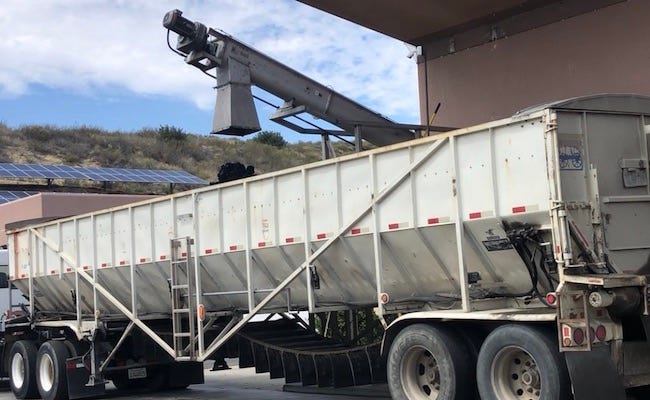 Processed sludge being loaded into a large freight truck.