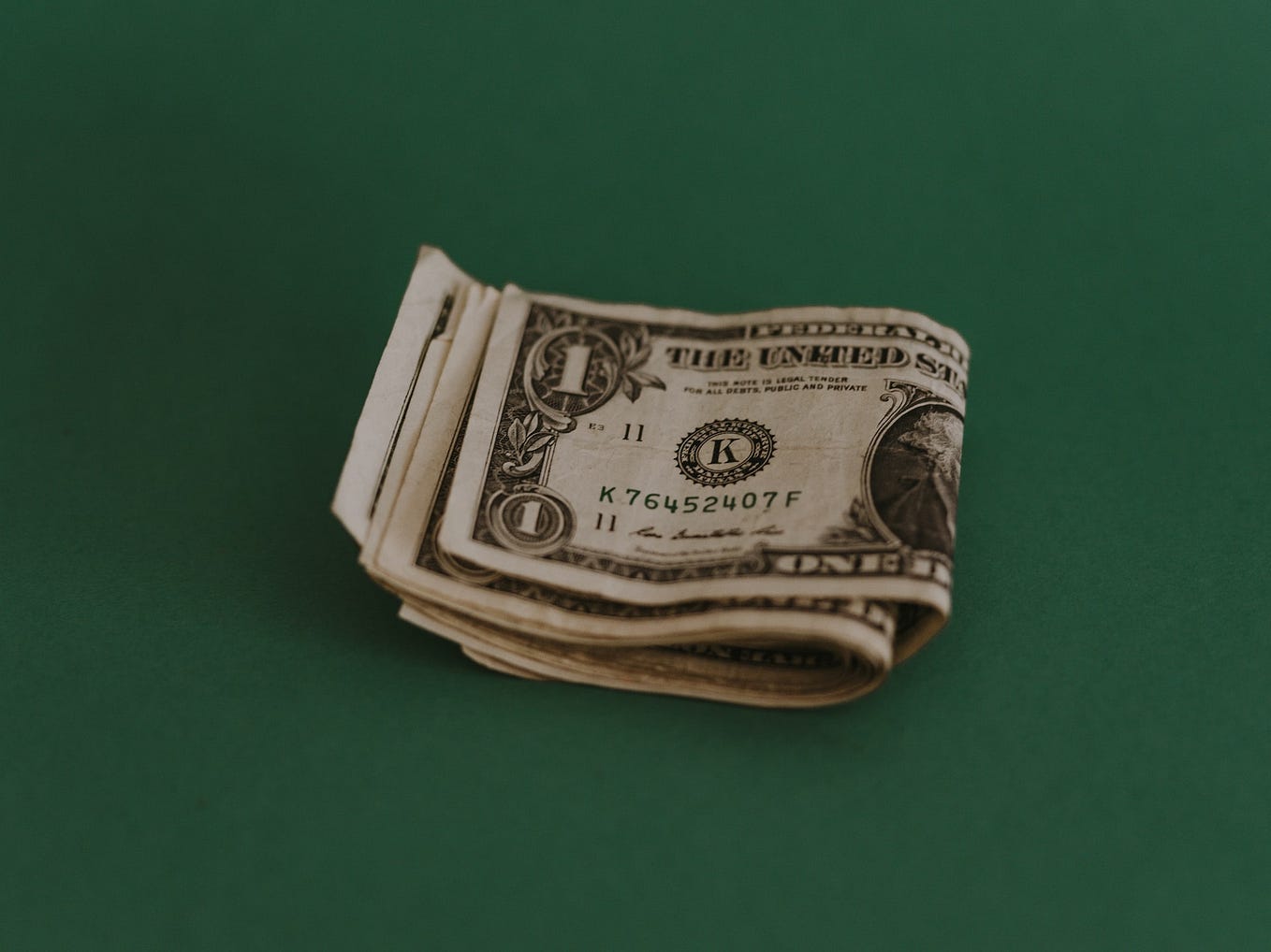 Pile of U.S. dollar bills on a dark green background