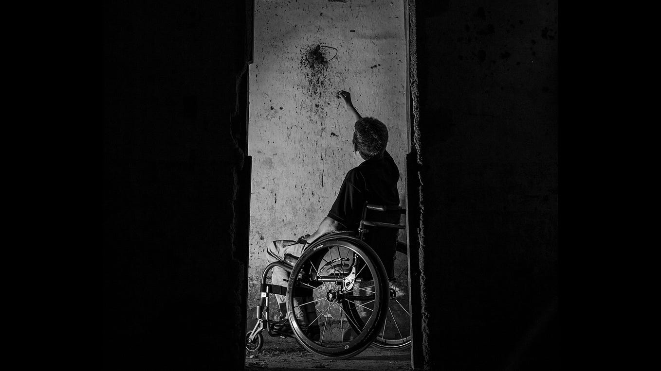Black and white picture of many in wheelchair reaching out to splatter on the wall.