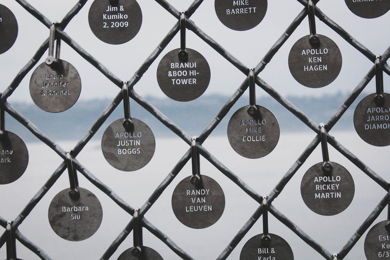 A cool picture of names on pendants dangling from a chain-link fence.