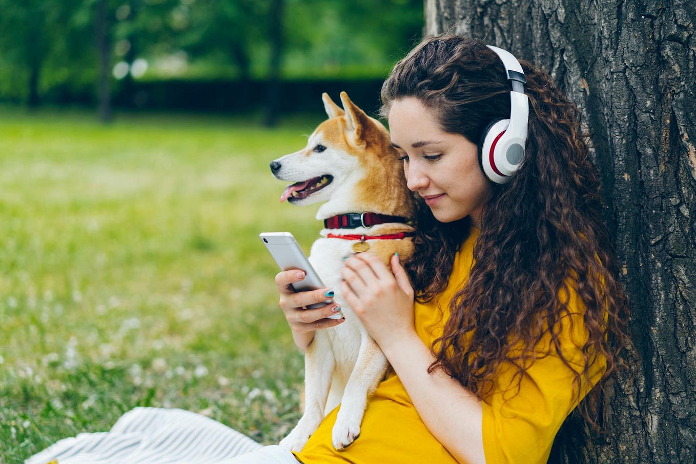Woman with a dog on her lap and listening to music with headphones.