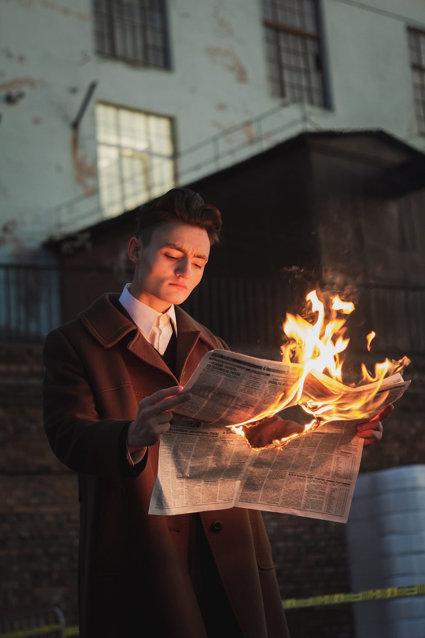 Person reading a newspaper that is on fire