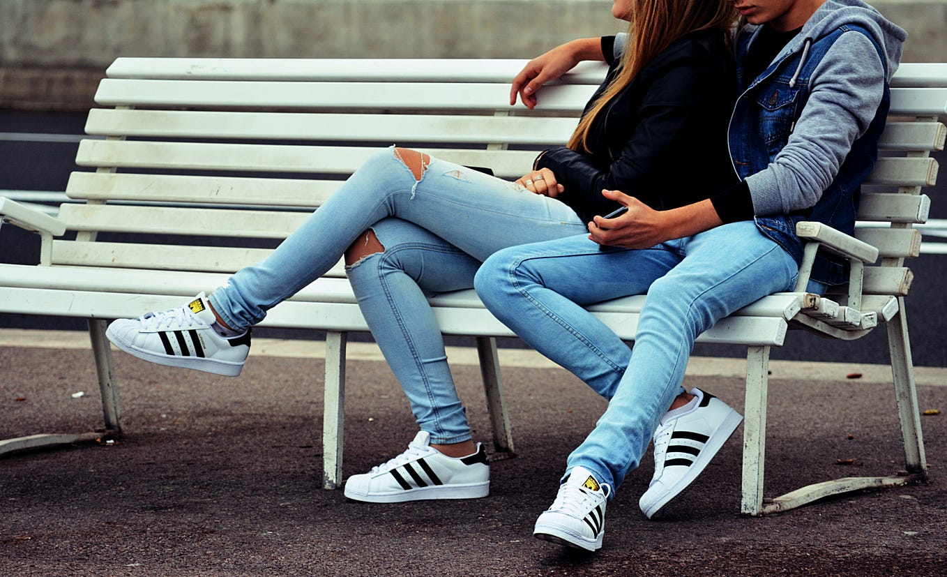 male and female young persons sitting on a bench