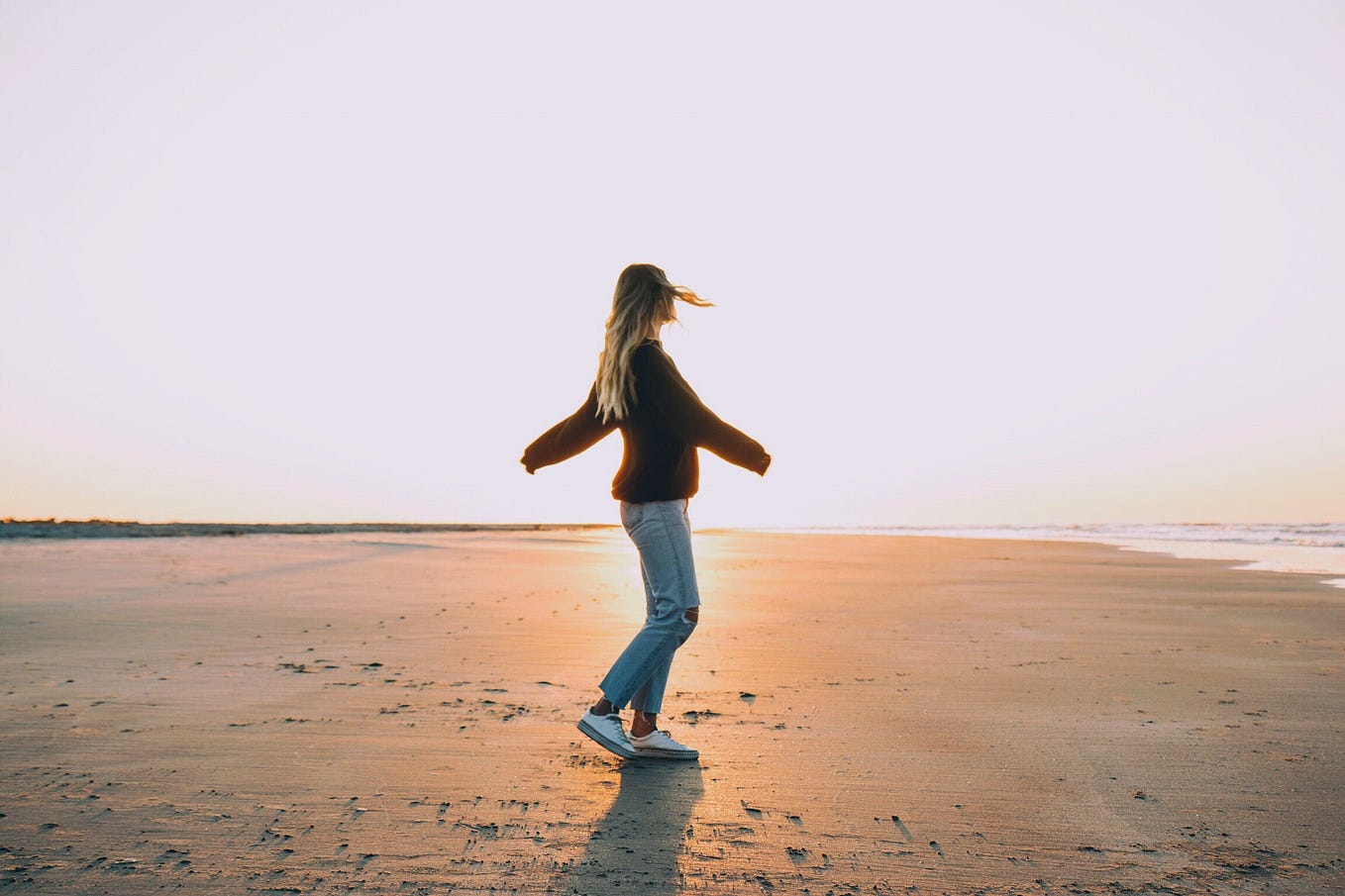 Girl spinning around on an empty beach