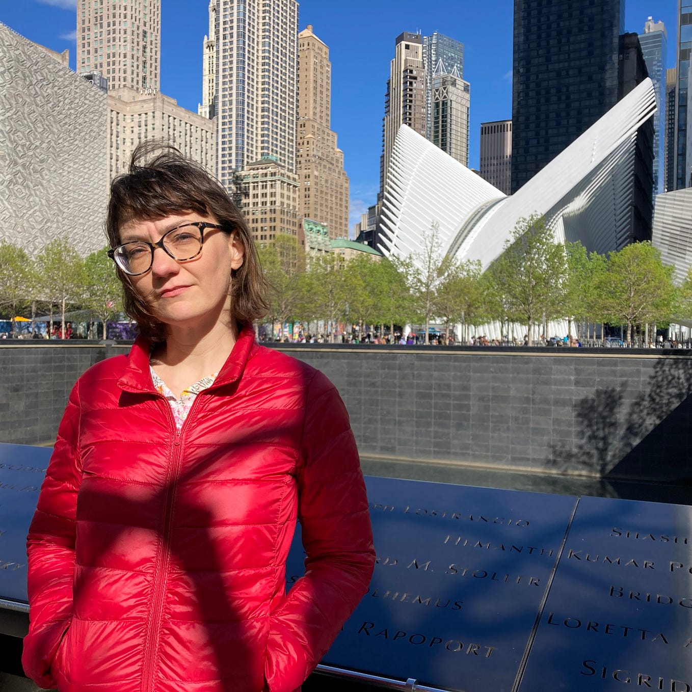 Photo of the author in a red jacket, standing in front of the 9/11 Memorial