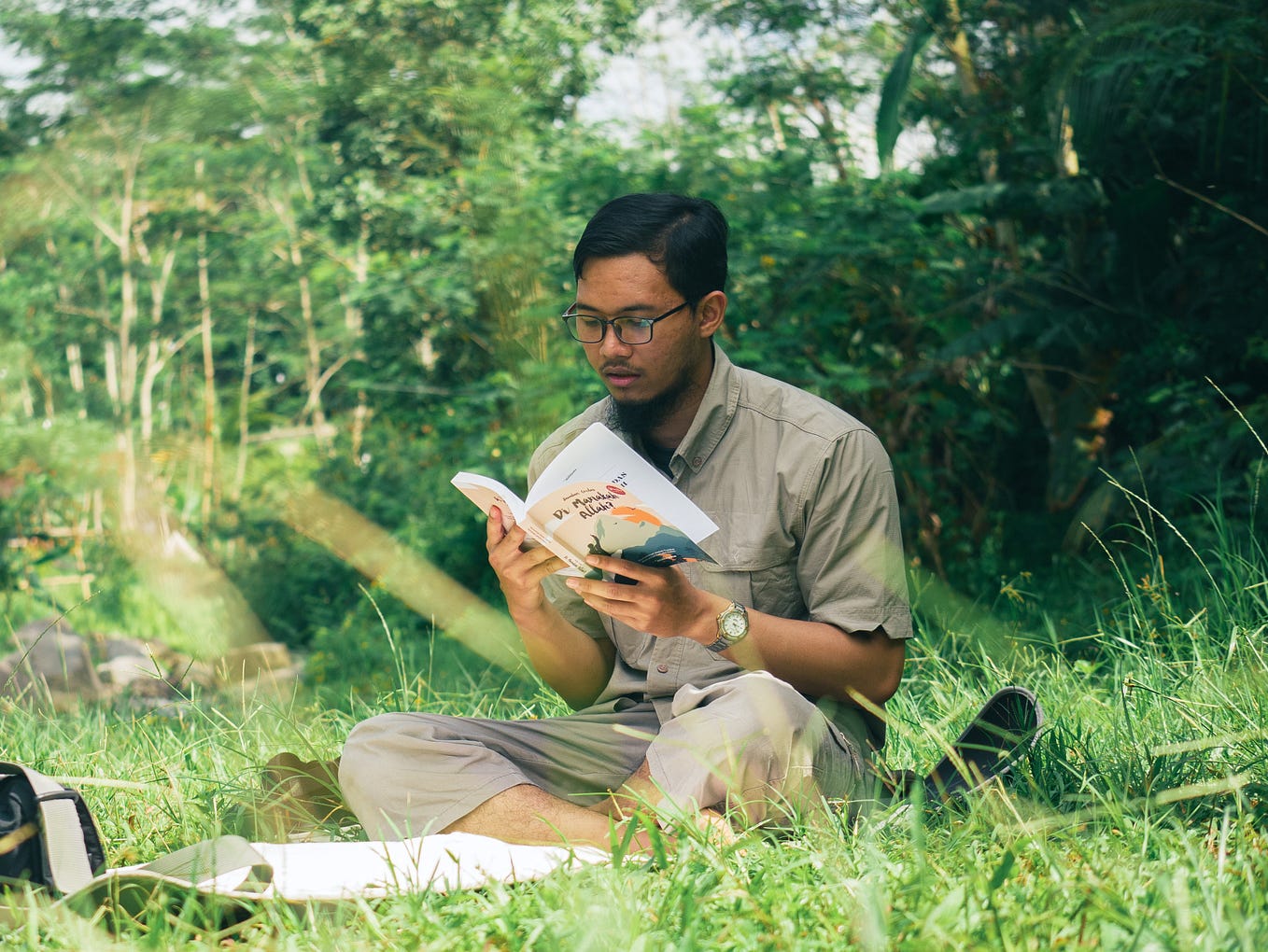 Young man reading book near river.