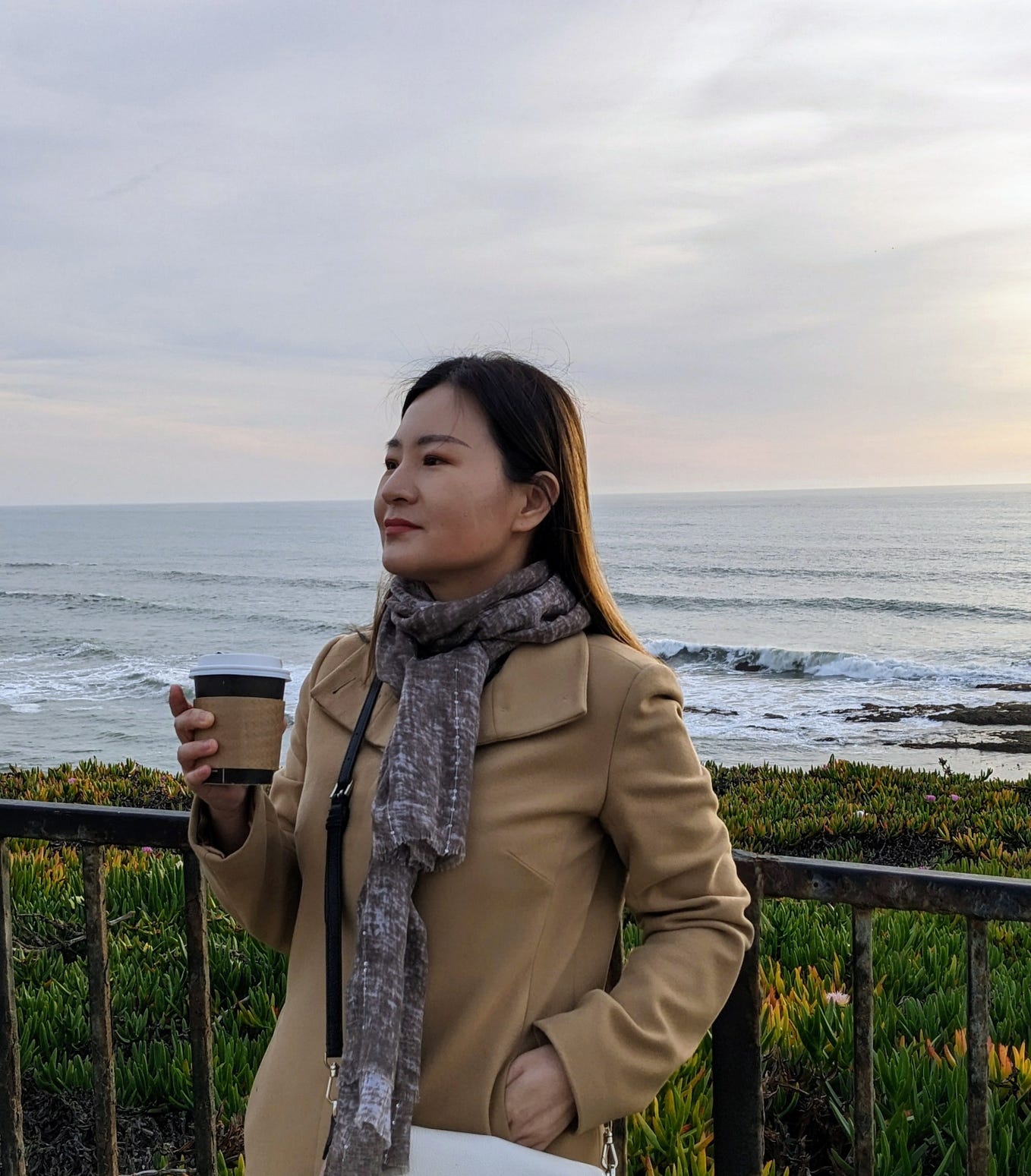 Felicia Wu holds a cup of coffee looking ahead on the Half Moon Bay coastline.