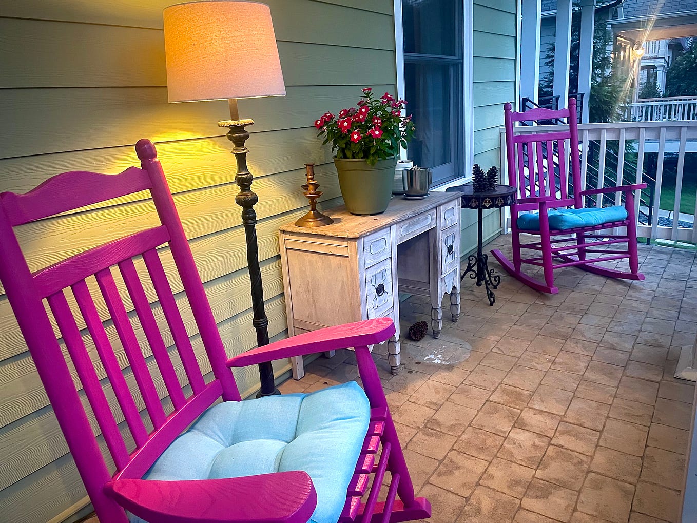 Two pink rocking chairs and some pink flowers on a front porch
