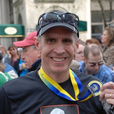 Rhett Bratt holding finishers medal after completing the 2011 Boston Marathon