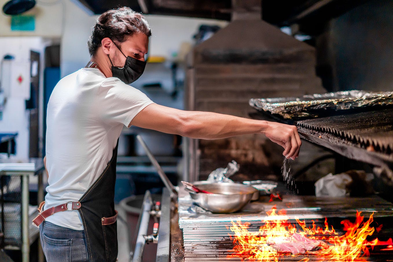 A Honduran man grills meat in the kitchen.