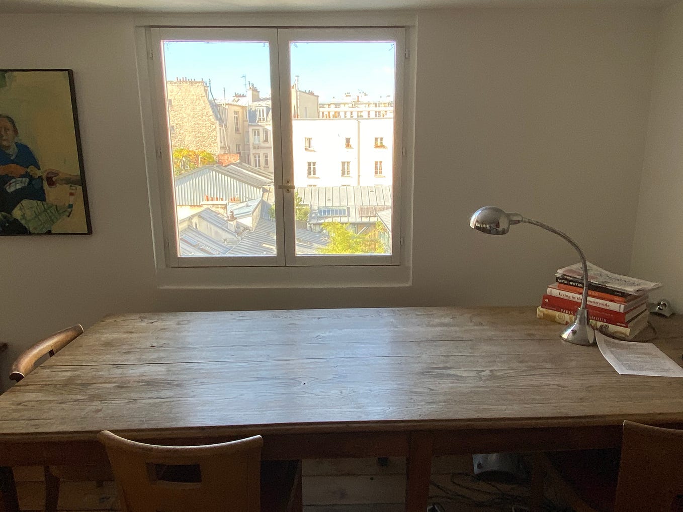A bare desk in front of a small window in a Paris garret.