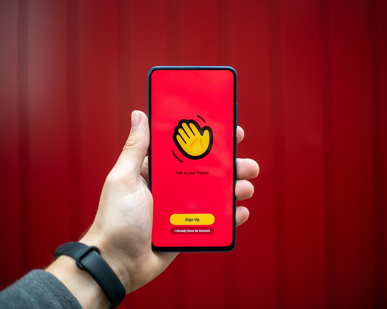 a hand holding a phone with a red background
