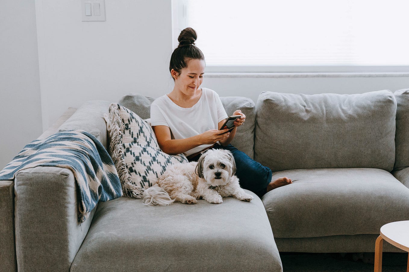 Millennial woman on phone with dog at home.