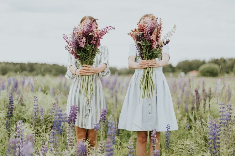 two teens in a field of wildflowers with bouquets of wildflowers covering their faces, practical parenting tips