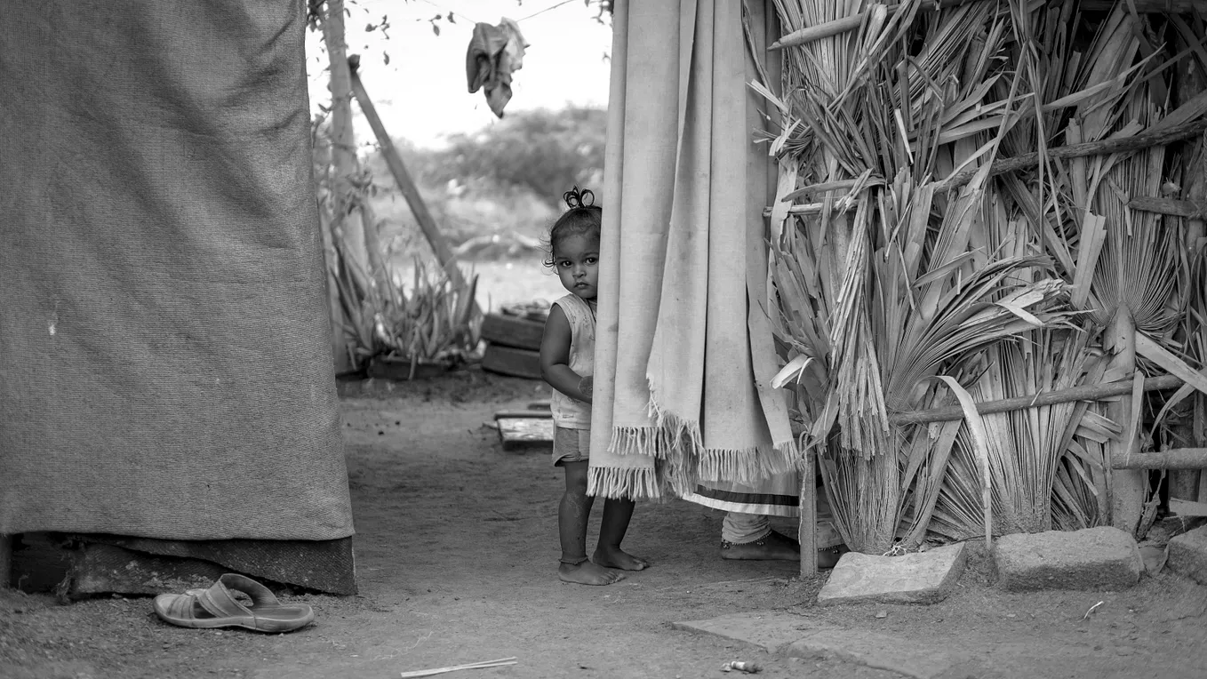 Poor Indian child peeking out from hovel…