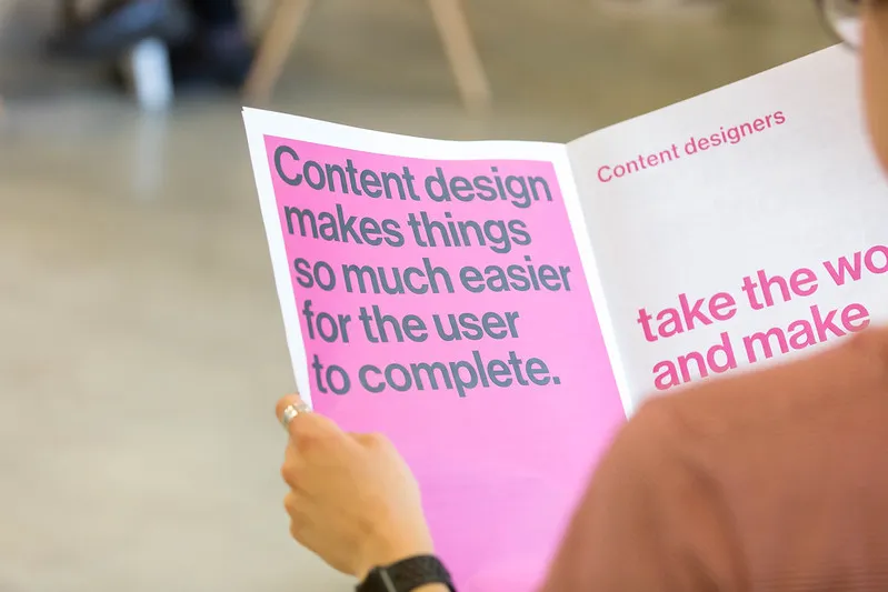 A woman reading a page that says “Content design makes it so much easier for the user to complete.”