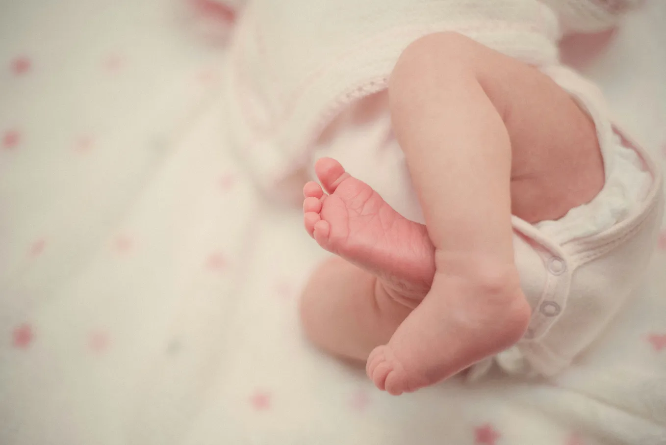 Baby in diapers lies in a bassinet.