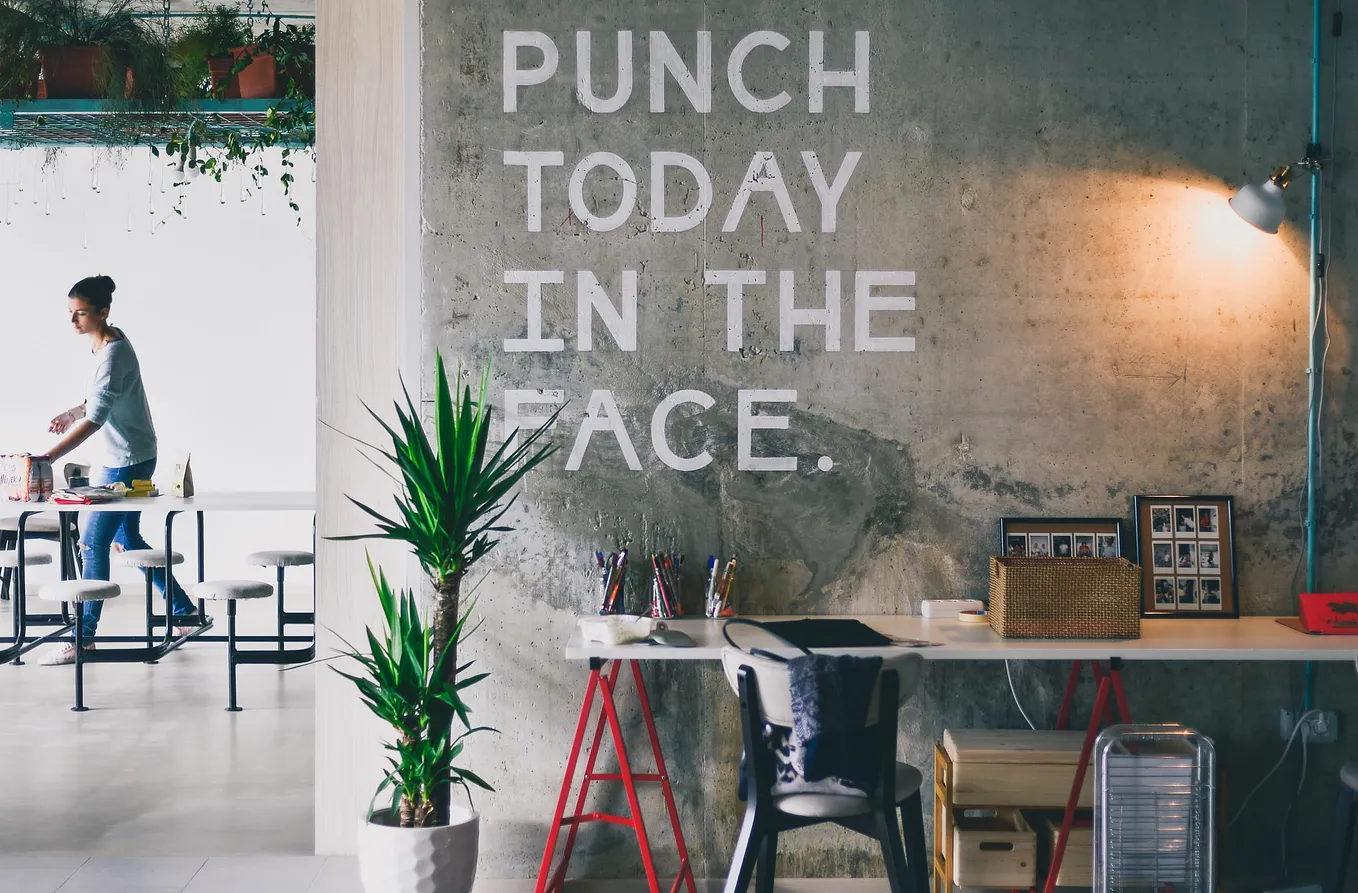 Office space, quote “Punch Today In The Face” written in capital letters on gray wall