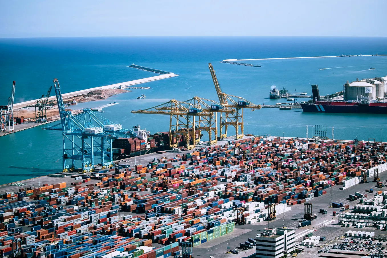 Aerial view of cargo cranes and shipping containers at a large commercial port.