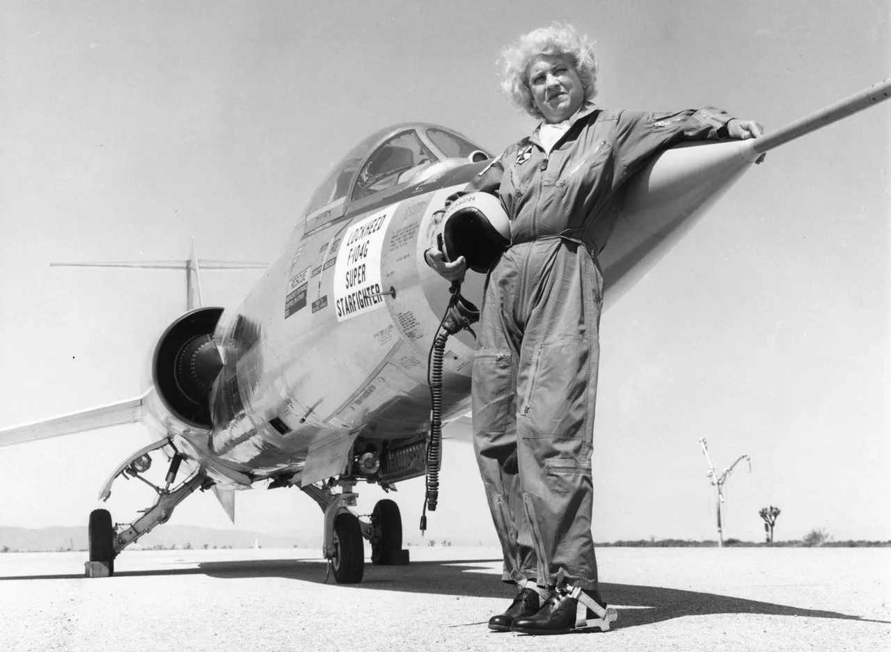 Black and white Photo of Jacqueline Cochran in flying uniform standing in front of Lockheed F-104G Super Starfighter plane on runway. Posted on mickey markoff 2024 article on women in aviation; credit — US San Diego Air & Space Museum