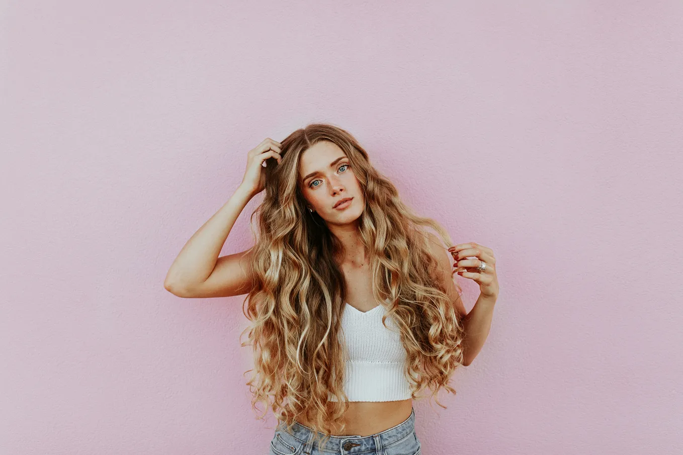 Girl with long curly hair against a mauve background