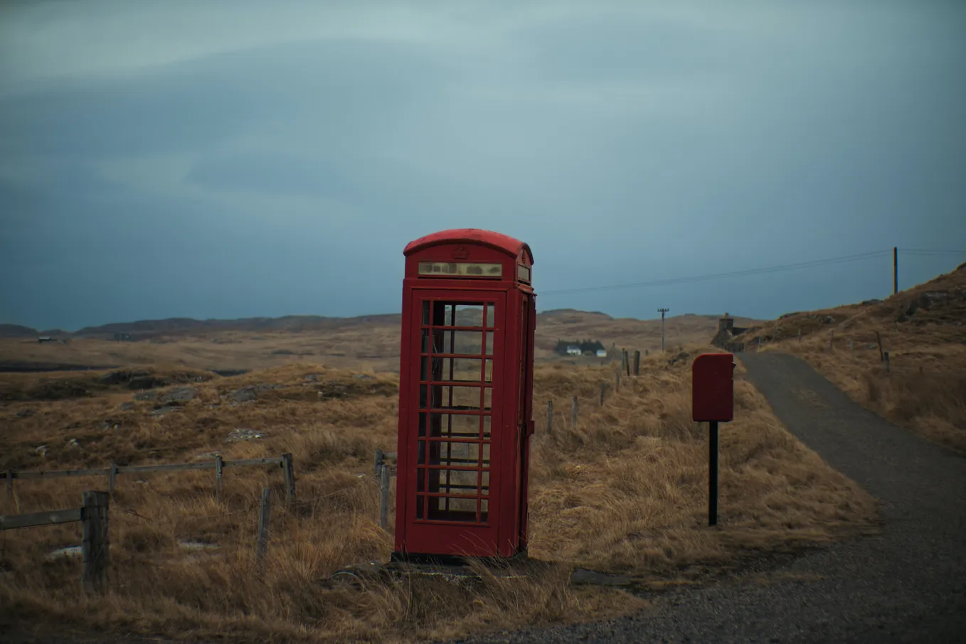 An abandoned red British phone booth in a barren landscape