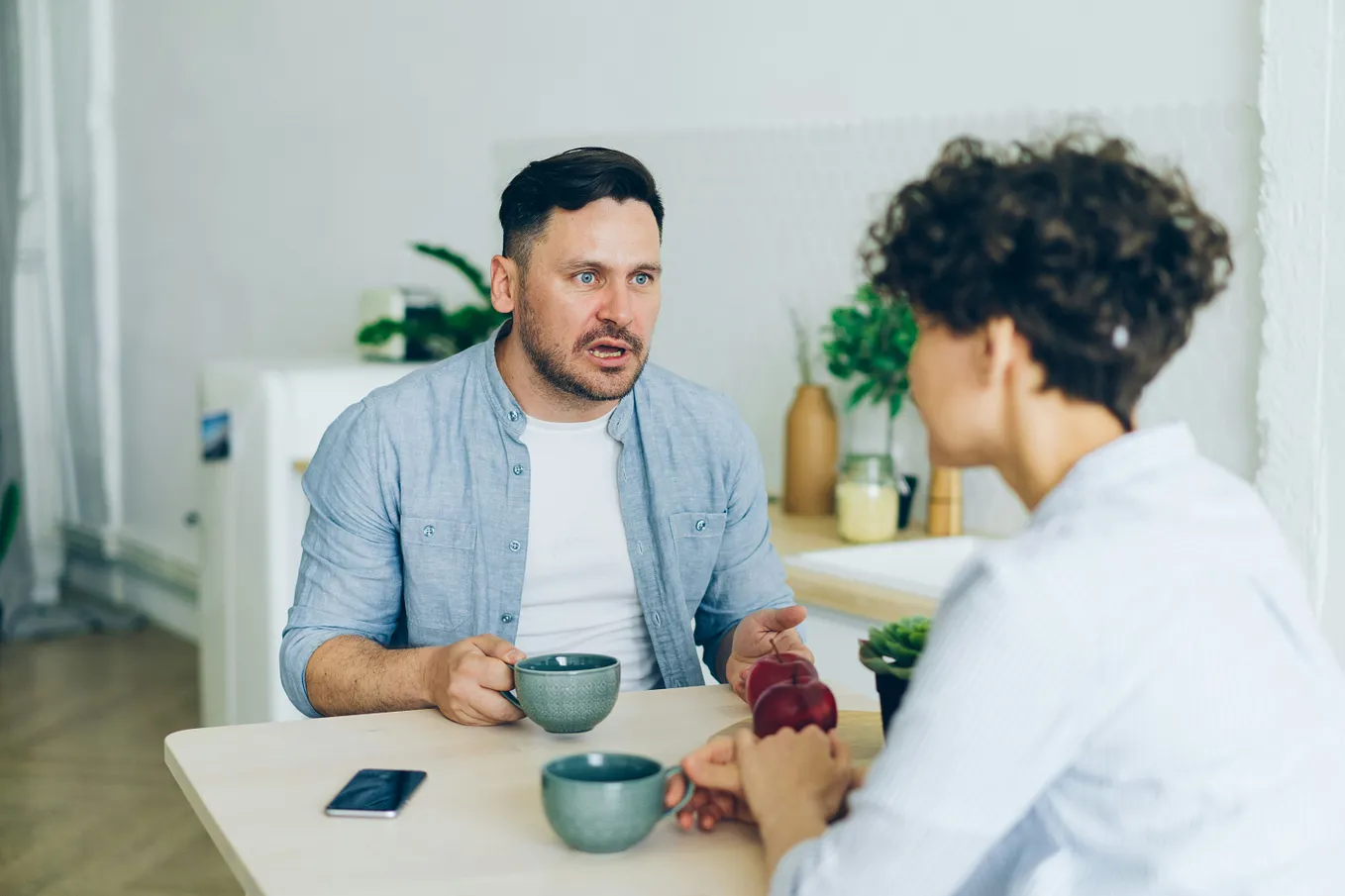 Two people sitting in a table drinking coffee